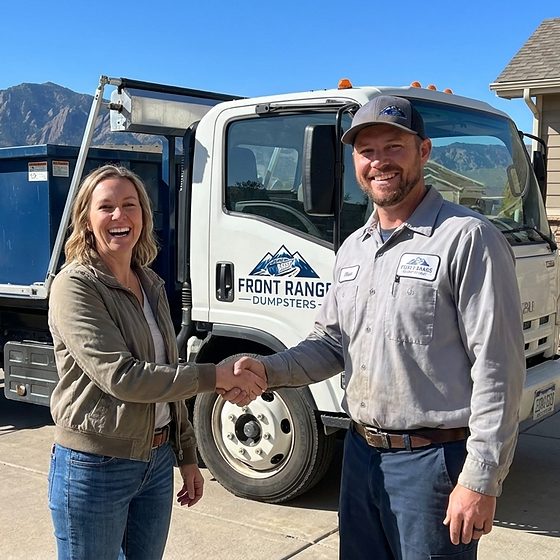 A Front Range Dumpsters driver shaking hands with a homeowner beside a delivered roll-off truck